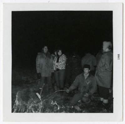 Photograph of people around campfire